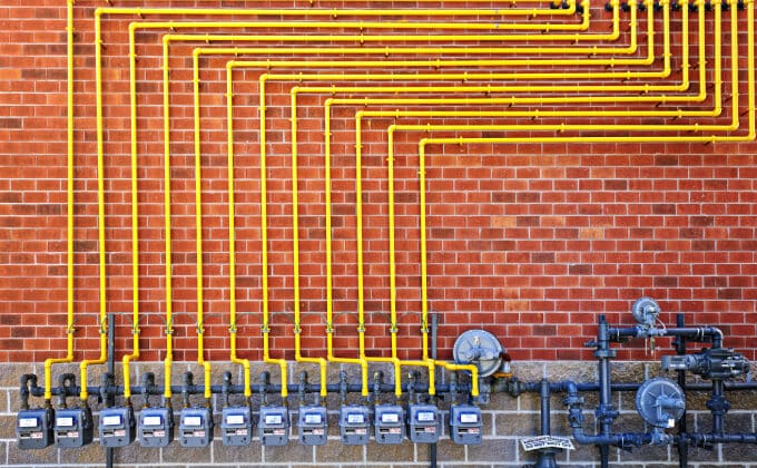 A maze of yellow gas distribution pipes set against a red brick wall.