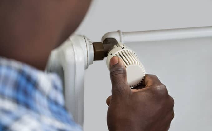 A person turns the knob on a gas radiator.