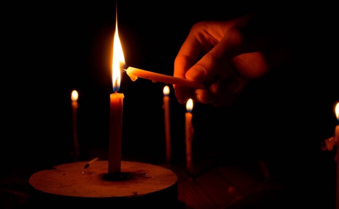 hand lighting candles in the darkness of a power outage|Hand lighting candles in the darkness of a power outage|Hand lighting candles in the darkness of a power outage