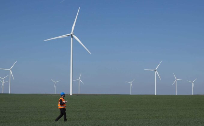 engineer walking across field with wind turbines in background|engineer walking across field with wind turbines in background