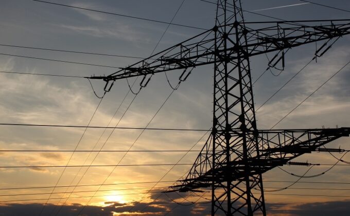 power lines and transmission tower against dramatic gray sky|