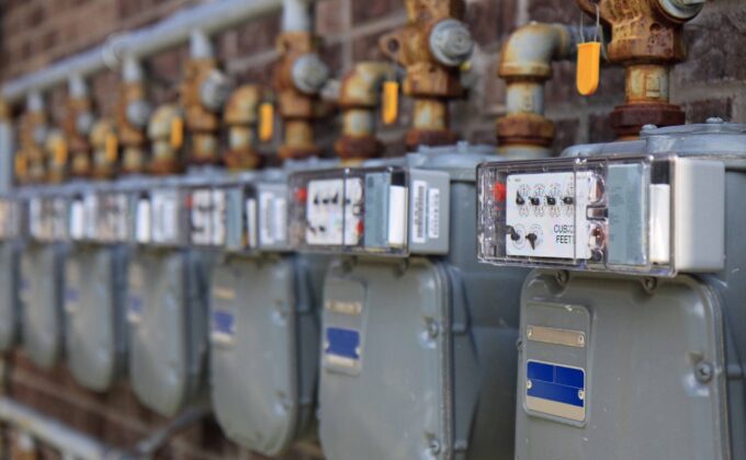 A row of gas meters on the wall of an apartment building