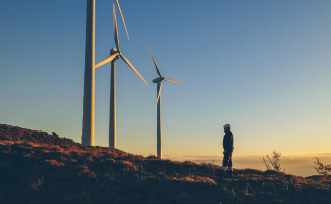 man next to wind turbines|man standing in front of wind turbines