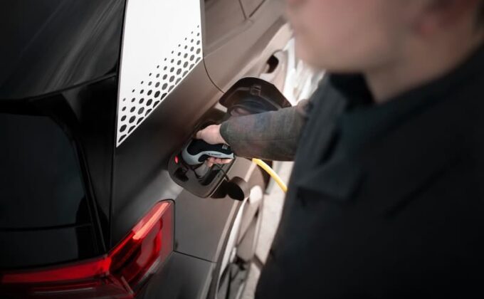 Close-up of a man charging a black electric car|