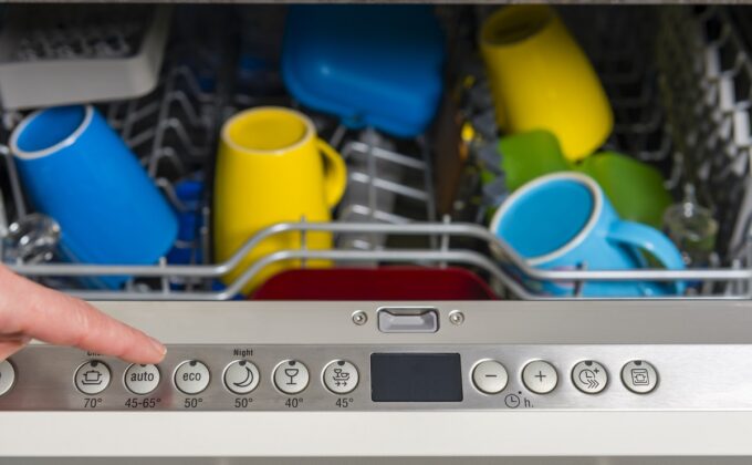Finger pressing eco setting on a dishwasher