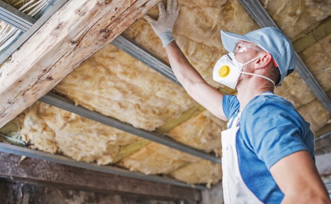 Man with protective mask and gloves testing insulation in ceiling