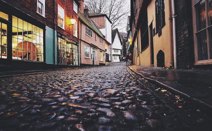 view up a cobblestone street lined with one-story buildings in a european town|view up a cobblestone street lined with one-story buildings in a european town