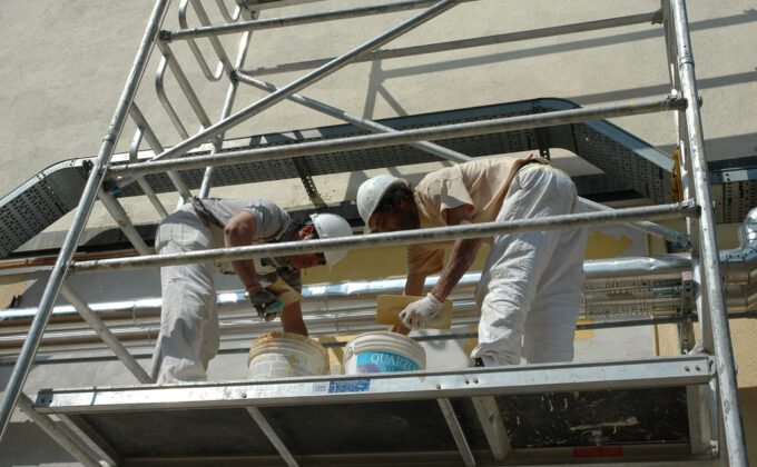 Workers on scaffolding doing building renovations in Italy