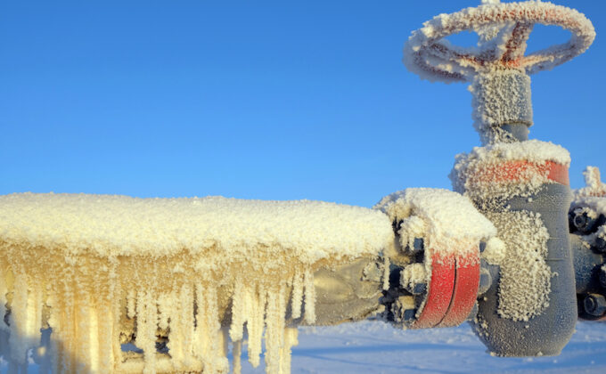 Frozen gas valve and high pressure pipe with icicles hanging off it|snowy trees and power lines