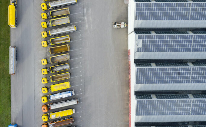 Aerial view of trucks and a large storehouse with solar panels on the rooftop.