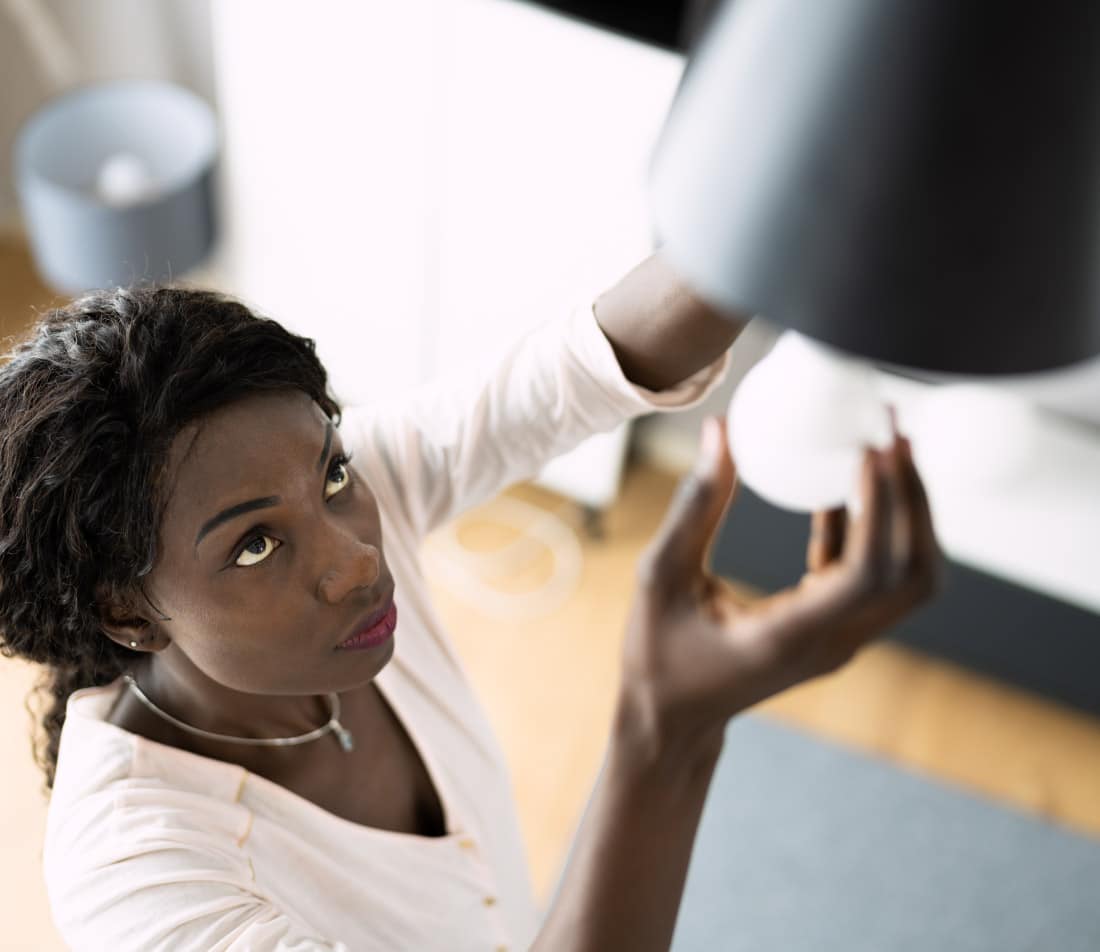 Woman changing a light bulb in a clean energy home