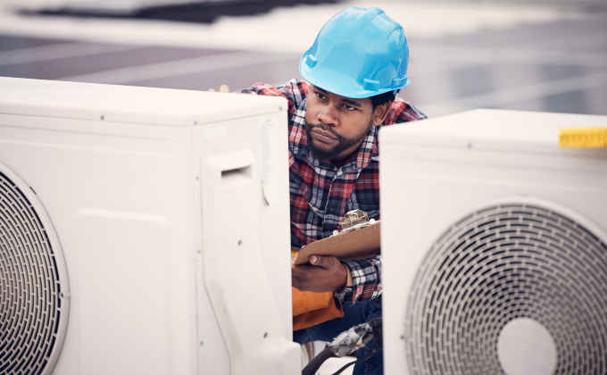 Man in blue hardhat working on heat pumps