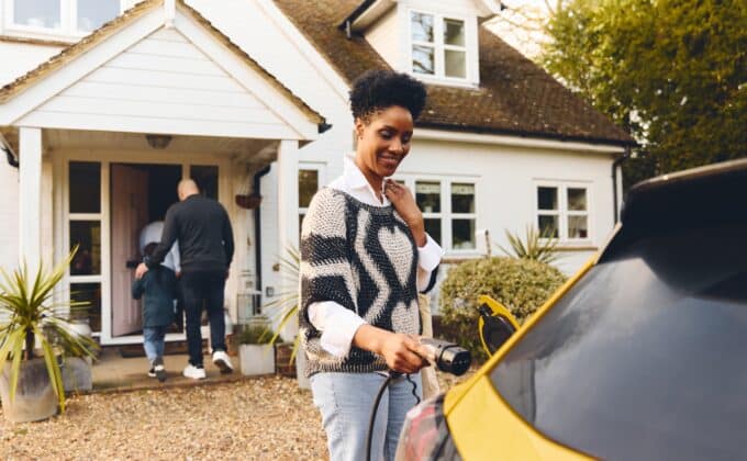 Woman plugging in electric charger into car