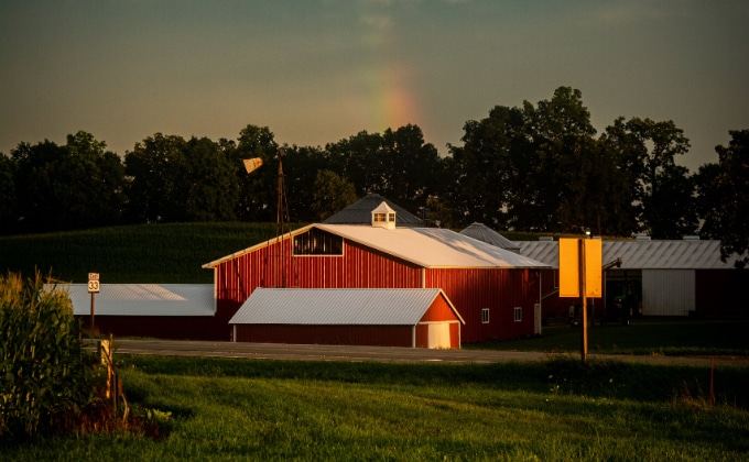 Red barn and farm buildings with rainbow