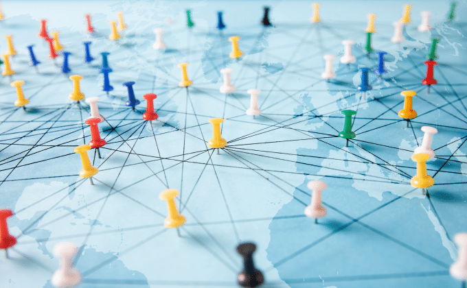 Colorful push pins create a network across a map in shades of blue.