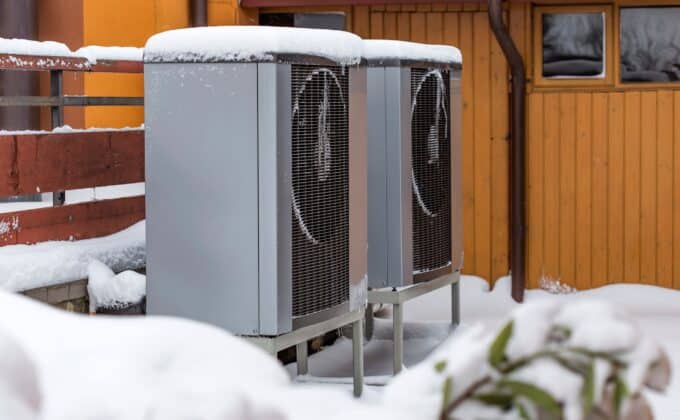 Two residential modern heat pumps buried in snow