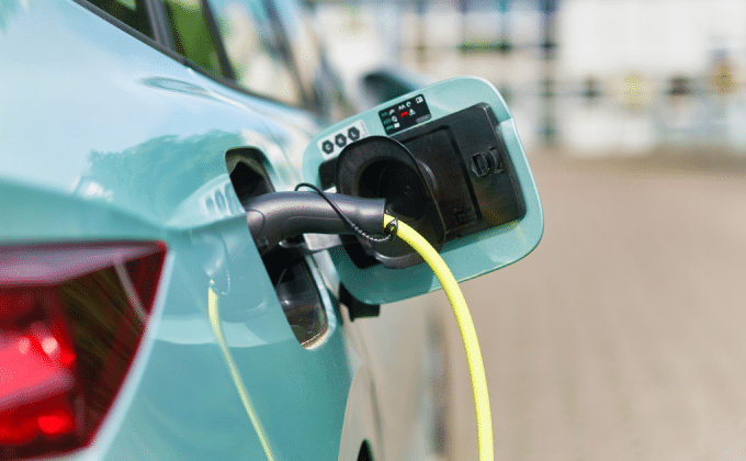 A close up on the charging port of an aqua electric car, which is plugged in to charge