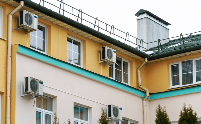 Air source heat pumps attached to the exterior of an apartment building.