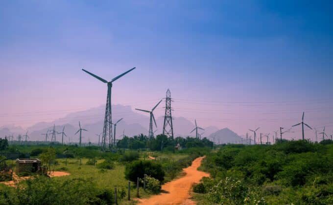 Beautiful view of Windmills or Wind Turbines farm in Nagercoil, South India. With a colorful sky and mountains as a background.