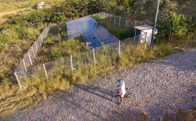 Homem andando de bicicleta perto de painéis solares em um projeto de energia sustentável no campo Man Riding Bicycle Near Solar Panels in Countryside Sustainable Energy Concept